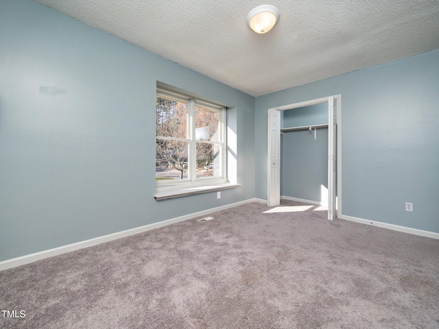 unfurnished bedroom with carpet floors, a textured ceiling, and a closet