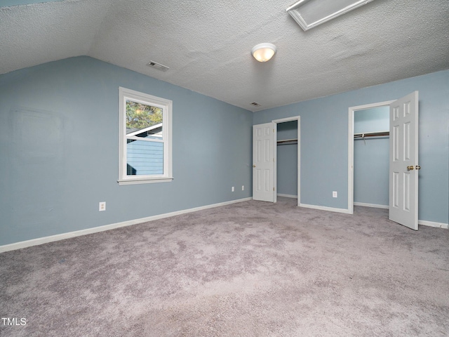 unfurnished bedroom featuring a textured ceiling, light carpet, and vaulted ceiling