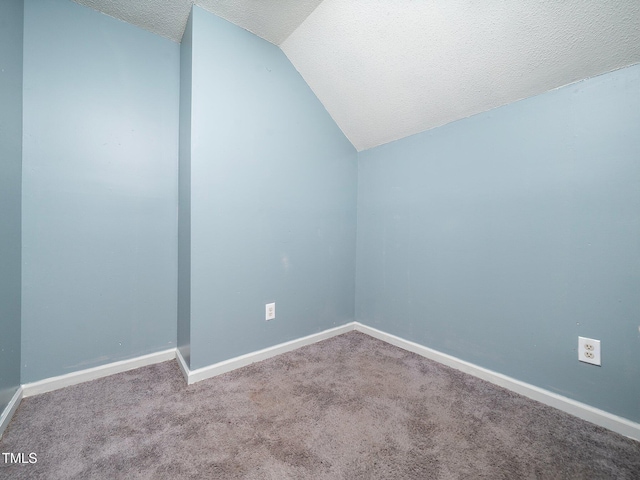 spare room featuring carpet floors, a textured ceiling, and vaulted ceiling