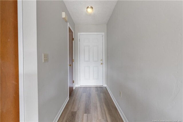 corridor with wood-type flooring and a textured ceiling