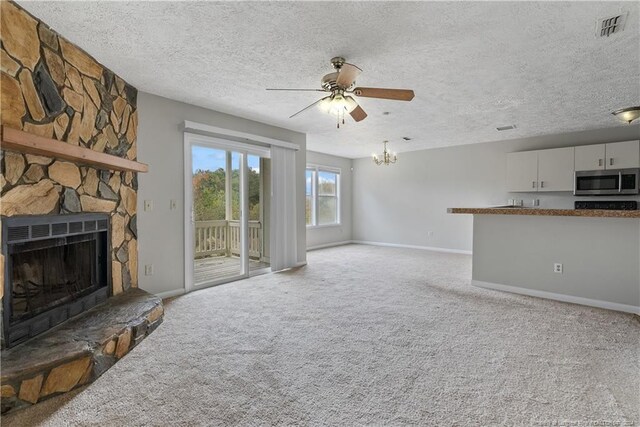 living room with a fireplace, light colored carpet, a textured ceiling, and ceiling fan with notable chandelier