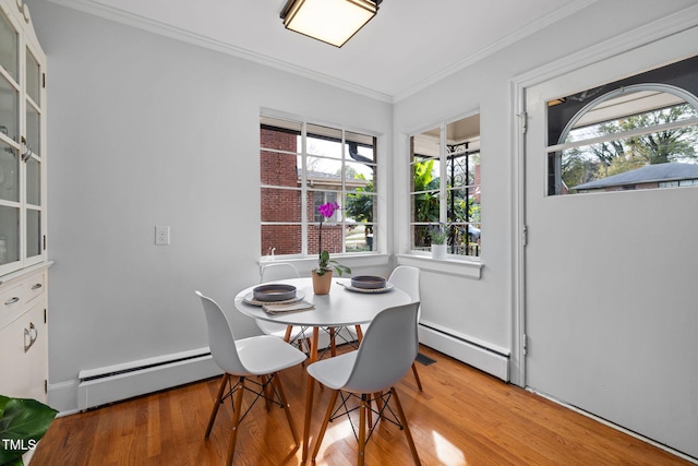 dining room with ornamental molding, light wood-type flooring, and a baseboard heating unit