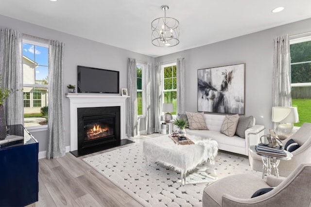 living room with an inviting chandelier, light hardwood / wood-style flooring, and a wealth of natural light