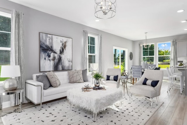 living room featuring light wood-type flooring, a wealth of natural light, and an inviting chandelier