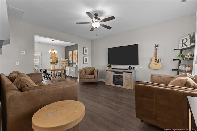 living room with dark hardwood / wood-style floors, a fireplace, and ceiling fan with notable chandelier