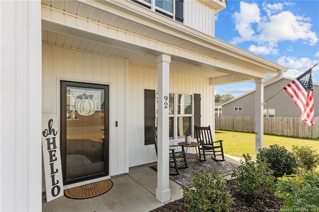 view of exterior entry featuring a lawn and a porch