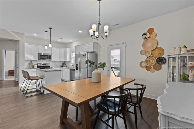 dining space featuring dark wood-type flooring and a notable chandelier