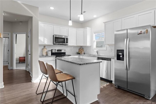 kitchen featuring white cabinets, appliances with stainless steel finishes, a kitchen island, and pendant lighting