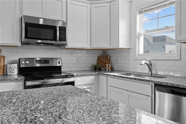 kitchen with light stone countertops, sink, white cabinets, and appliances with stainless steel finishes