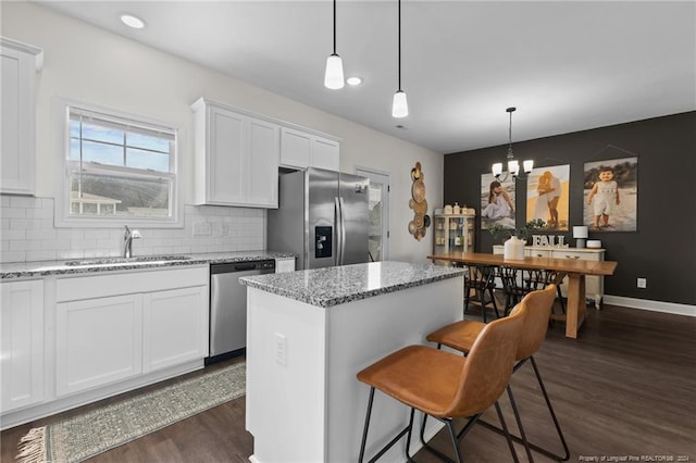 kitchen featuring white cabinets, a kitchen island, hanging light fixtures, and appliances with stainless steel finishes