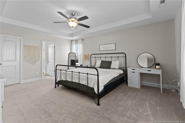 carpeted bedroom featuring ensuite bathroom, a raised ceiling, and ceiling fan