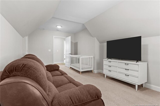 bedroom featuring a crib, light carpet, and vaulted ceiling