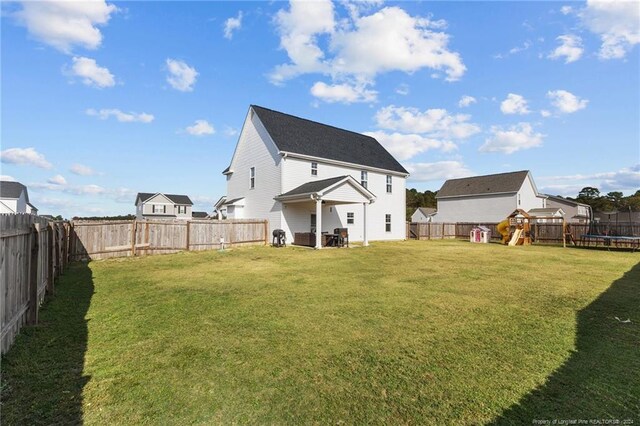 rear view of house with a yard, a playground, and a trampoline