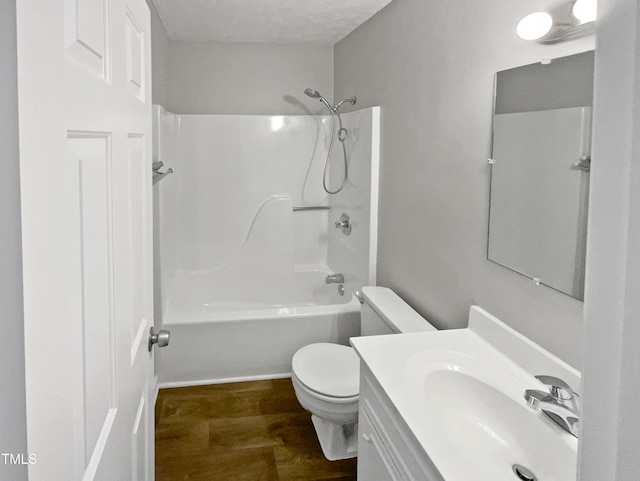 full bathroom with hardwood / wood-style floors, shower / bathing tub combination, vanity, toilet, and a textured ceiling