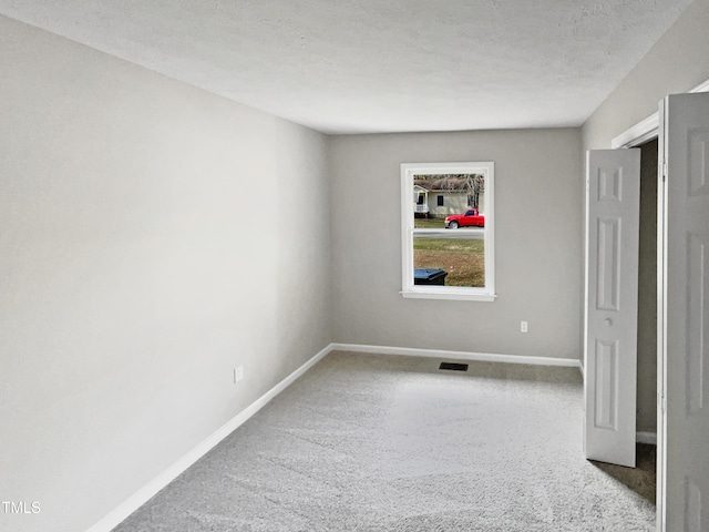 unfurnished room with a textured ceiling and carpet floors