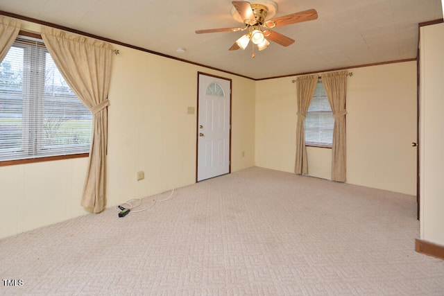 carpeted empty room featuring ceiling fan and crown molding