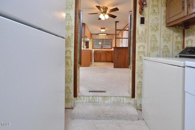 kitchen with independent washer and dryer, light colored carpet, ceiling fan, and white fridge