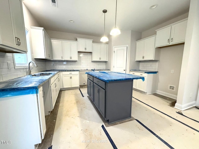 kitchen featuring a kitchen island, a sink, visible vents, baseboards, and dark countertops