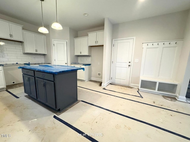 kitchen featuring decorative light fixtures, backsplash, white cabinetry, a kitchen island, and baseboards