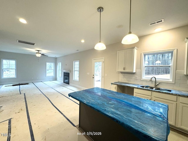 kitchen with baseboards, visible vents, backsplash, and a sink