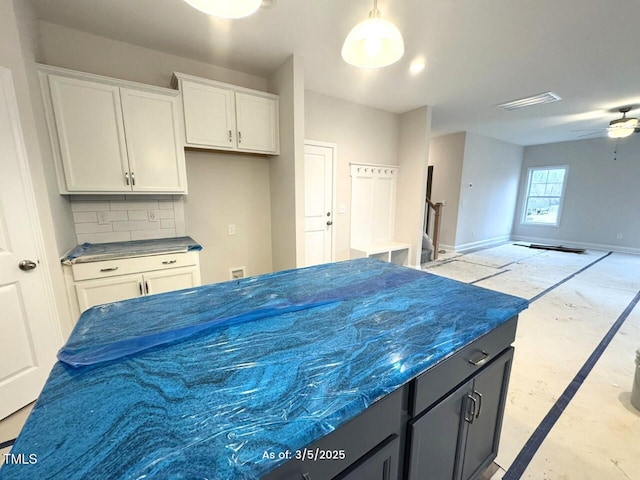 kitchen featuring baseboards, decorative backsplash, unfinished concrete floors, open floor plan, and white cabinetry