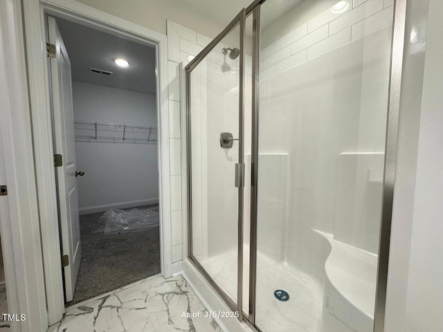 bathroom featuring marble finish floor, visible vents, a walk in closet, and a stall shower