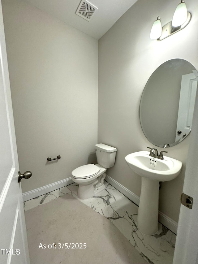 bathroom featuring toilet, marble finish floor, visible vents, and baseboards