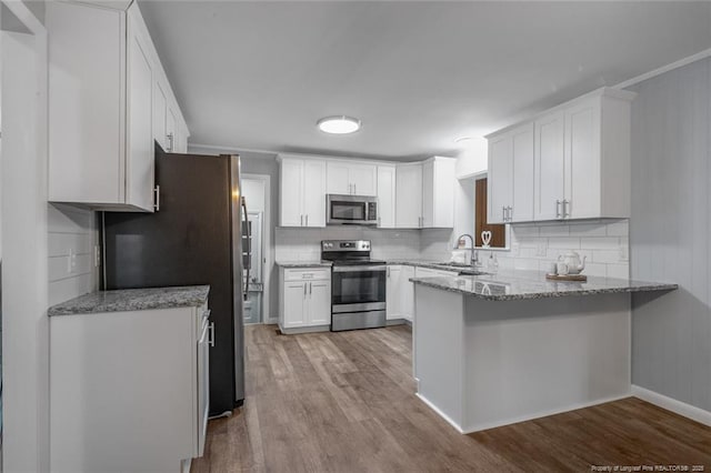 kitchen with sink, white cabinetry, stainless steel appliances, light stone counters, and light hardwood / wood-style floors