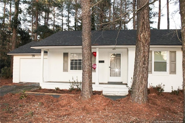 ranch-style house featuring a garage and roof with shingles