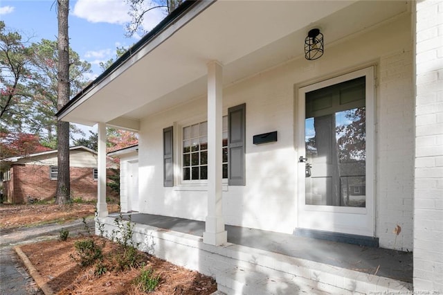 view of exterior entry with covered porch and brick siding