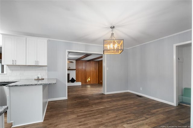 unfurnished dining area with a chandelier, dark wood-style flooring, baseboards, and crown molding