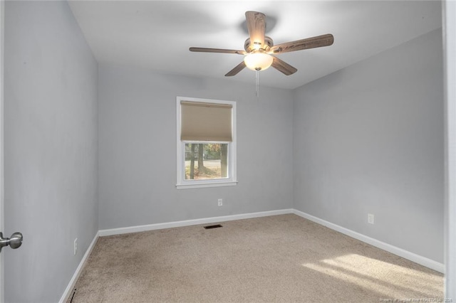 carpeted spare room with a ceiling fan, visible vents, and baseboards