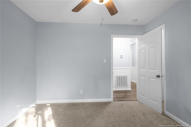 carpeted empty room with visible vents, ceiling fan, and baseboards