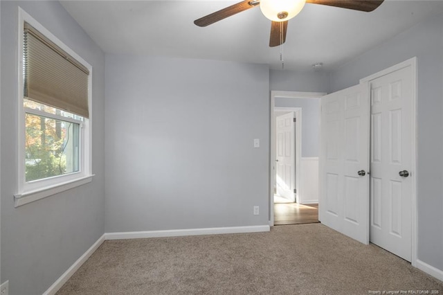 unfurnished bedroom featuring light carpet, ceiling fan, and baseboards