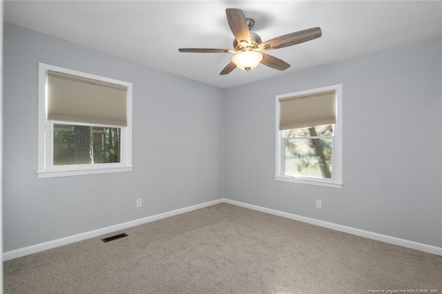 carpeted empty room featuring visible vents, ceiling fan, and baseboards