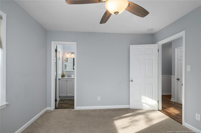 unfurnished bedroom featuring baseboards, dark carpet, a ceiling fan, and ensuite bathroom