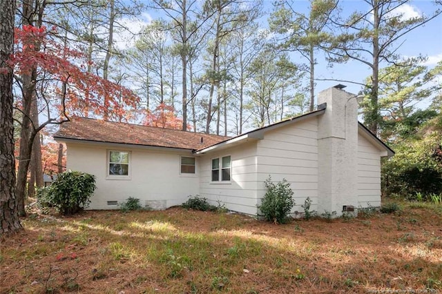 view of property exterior with crawl space, a chimney, and a yard