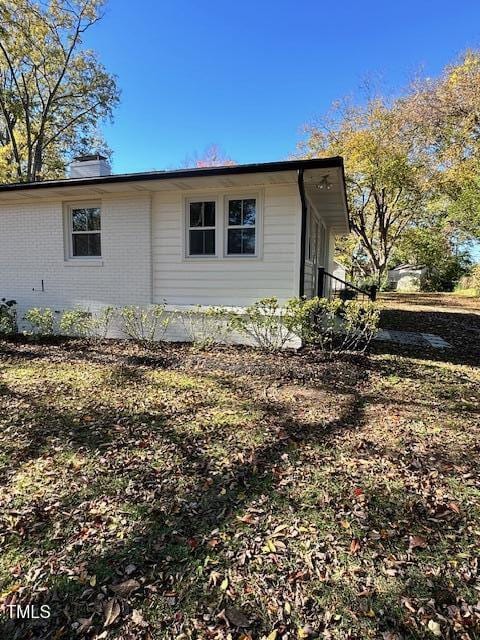 445 N Dunn St, Angier, NC 27501 - view of home's exterior featuring a chimney and brick siding