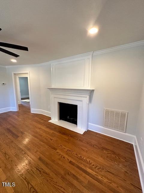 unfurnished living room featuring crown molding, ceiling fan, and dark wood-type flooring