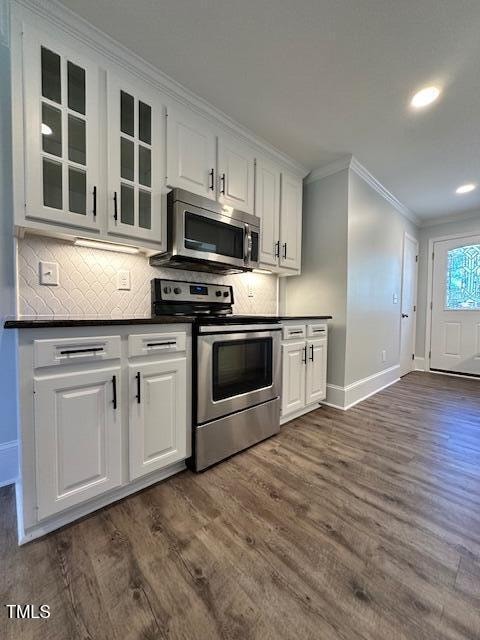 kitchen featuring white cabinetry, dark hardwood / wood-style flooring, ornamental molding, and appliances with stainless steel finishes