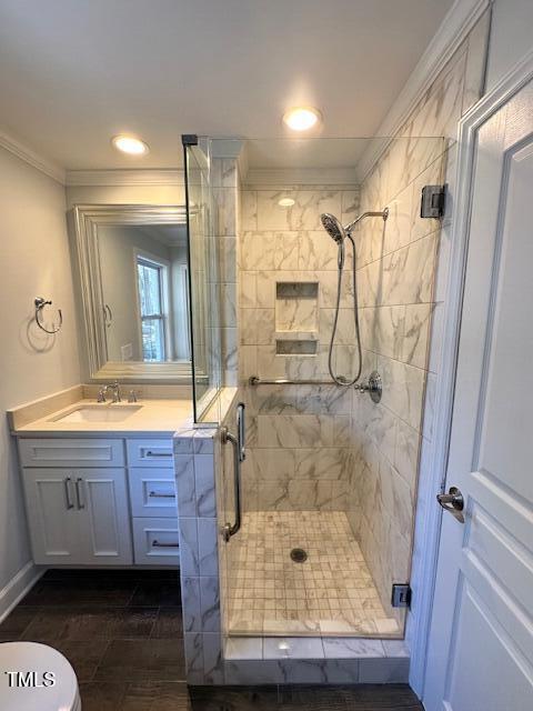 bathroom with a shower with shower door, wood-type flooring, crown molding, and vanity