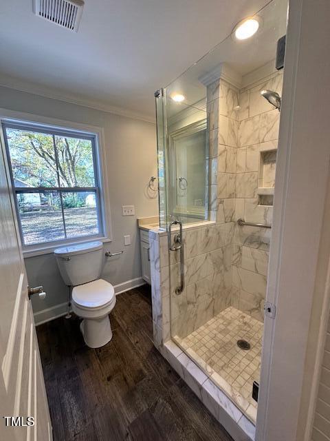 bathroom featuring vanity, crown molding, hardwood / wood-style flooring, toilet, and a tile shower