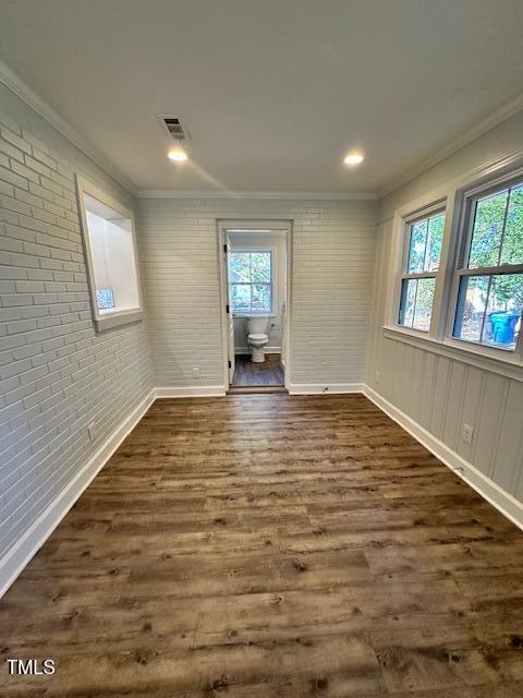 445 N Dunn St, Angier, NC 27501 - empty room with crown molding, plenty of natural light, dark wood finished floors, brick wall, and baseboards