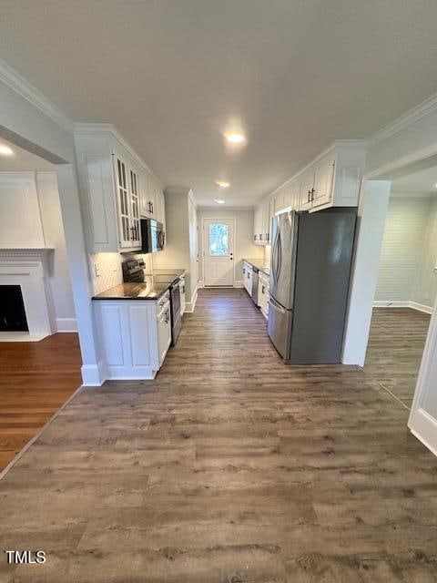 kitchen featuring stainless steel appliances, dark hardwood / wood-style flooring, decorative backsplash, white cabinets, and ornamental molding