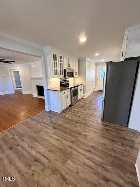 kitchen with crown molding, white cabinetry, dark hardwood / wood-style flooring, and stainless steel appliances