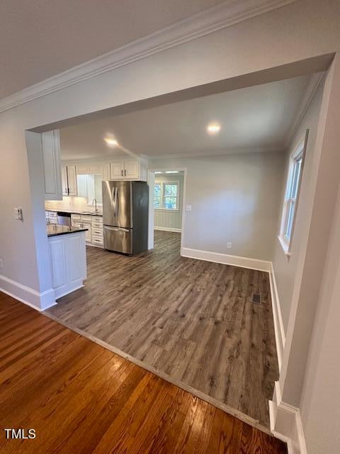 kitchen featuring white cabinetry, dark hardwood / wood-style flooring, crown molding, and appliances with stainless steel finishes