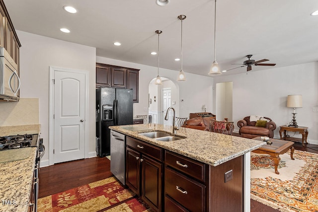 kitchen with dark brown cabinetry, ceiling fan, sink, stainless steel appliances, and a center island with sink