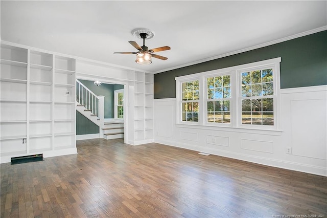 unfurnished living room featuring ceiling fan, crown molding, dark wood-type flooring, and built in shelves