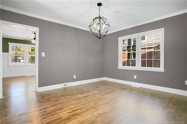 empty room featuring ceiling fan with notable chandelier, wood-type flooring, and ornamental molding