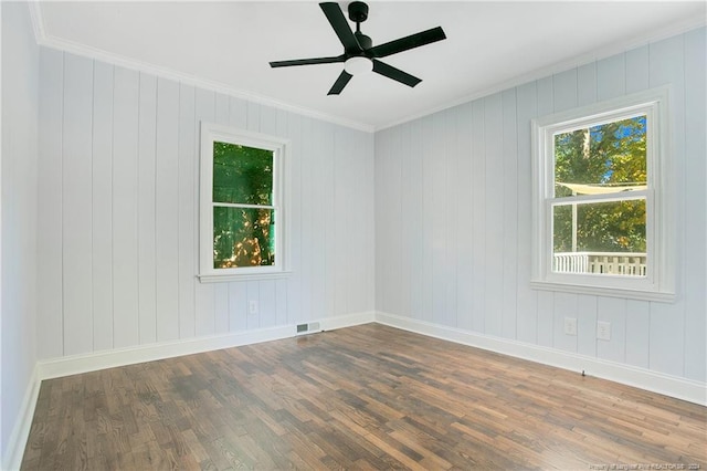 empty room with dark hardwood / wood-style floors, ceiling fan, ornamental molding, and wooden walls